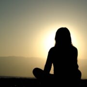 silhouette of woman sitting, watching sun rise